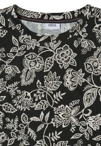 Tissu noir avec motif floral et feuillage blanc complexe, présentant différentes fleurs stylisées et feuillages, col rond avec une étiquette "CECIL".