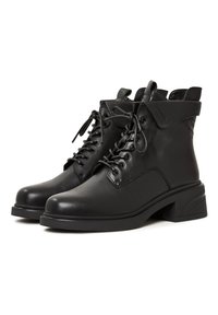 Bottines noires en cuir avec un bout arrondi, un laçage à l'avant et un talon carré. Elles présentent un revers replié et des accents de couture discrets.