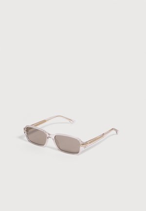 Lunettes de soleil rectangulaires avec verres teintés marron clair et monture en plastique beige transparent posées sur une surface blanche.