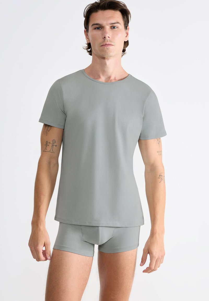 Maglietta grigia a maniche corte e boxer coordinati, realizzati in materiale morbido. La maglietta presenta un collo rotondo e una texture liscia.