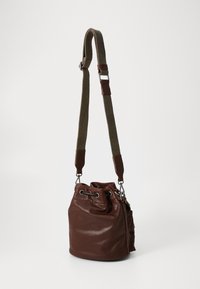 Brown leather bucket bag with a textured finish, an adjustable fabric strap, and metal hardware accents such as grommets and clasps.