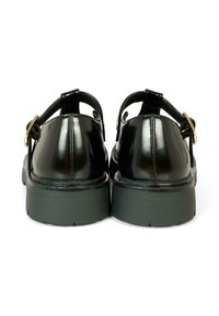 Chaussures en cuir verni noir avec un bout rond, une sangle réglable et une épaisse semelle en caoutchouc noir. Présentent une finition brillante et un matériel minimal.
