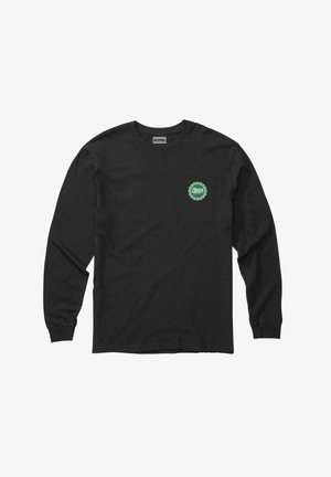 Camiseta de algodón de manga larga negra con un logo circular verde en el área del pecho izquierdo. Corte clásico con puños acanalados. Textura suave.