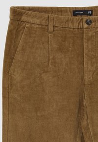 Pantaloni in velluto a coste marroni con una finitura testurizzata, dotati di tasche frontali e chiusura con bottone in vita. L'etichetta riporta "CALLIOPE".