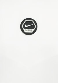 Μαύρο εξαγωνικό λογότυπο της Nike με λευκό σχήμα swoosh και κείμενο σε λευκό φόντο.