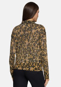 Sweter w panterkę w kolorze złotym i czarnym, z prążkowanym dołem, długimi rękawami i miękkim, teksturowanym dzianinowym materiałem.
