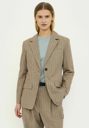 Beiger Nadelstreifenblazer aus leichtem Stoff, mit einreihiger Knopfleiste, Reverskragen und zwei Vordertaschen. Kombiniert mit einem hellblauen Oberteil.