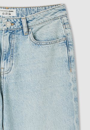 Jeans in denim azzurro chiaro presentano una finitura sbiadita, due tasche e piccoli chiodini decorativi. Completati con cuciture arancioni e un bottone argento.