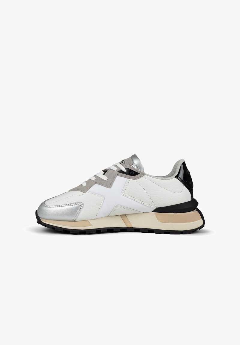 Vit sneaker med silver- och gråaccenter, texturerad läderöverdel, svart hälen och en tjock gummisula med en beige sektion.