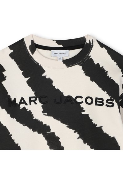 Zwart-witte T-shirt met een gedurfde, abstracte patroon en de merknaam "MARC JACOBS" prominent in het midden weergegeven.