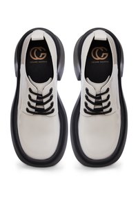 Chaussures blanches en cuir à lacets avec semelles épaisses noires, lacets noirs et logo "Cesare Gaspari" sur les semelles intérieures noires, vues de dessus.