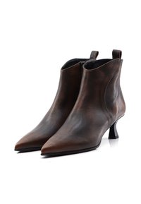 Pár hnědých kožených kotníkových bot s špičatými špičkami, bočními zipy, poutky na vytahování a nízkými tvarovanými podpatky na bílém pozadí.