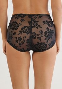 Černé průhledné kalhotky s vysokým pasem, zdobené květinovým vzorem, zakončené mašlí a s hladkou texturou. Zadní pohled ukazuje pokrytí a design.