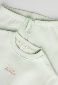 Lysgrønt bomuldsoutfit med en crewneck sweatshirt med broderet tekst og matchende bukser med elastisk talje og snor.