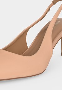 Μπεζ γόβα slingback με μυτερή μύτη και λεπτό τακούνι στιλέτο, με λεία υφή δέρματος.