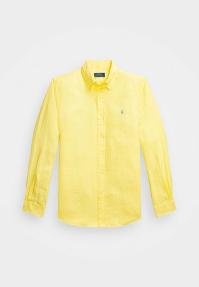 Camisa de botão amarela de manga longa, feita de tecido leve. Apresenta um colarinho pontudo e um pequeno logo bordado no lado esquerdo do peito.