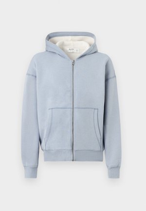 Hellblauer Kapuzenpullover mit Reißverschluss, Vordertaschen und einem cremefarbenen Innenfutter der Kapuze, vor neutralem Hintergrund dargestellt.