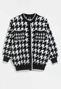 Svart och vit houndstooth-mönstrad cardigan, tillverkad av fluffigt material, med knäppning fram, två fickor och grå ribbade kanter.
