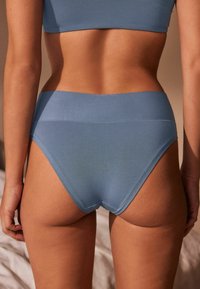 Helle blaue, hochgeschnittene Unterwäsche mit einem glatten, elastischen Bund und weichem Stoff, von hinten betrachtet, das ein einfaches, nahtloses Design zeigt.