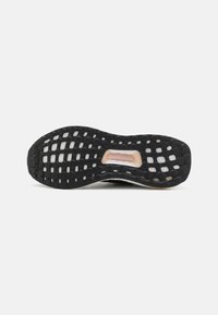 Black sneaker sole with a textured design featuring circular cutouts and a flexible, rubberized material. Includes a visible torsion system section.