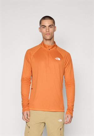 Chemise zippée à manches longues orange pour homme, en tissu texturé, avec un col haut et le logo North Face sur la poitrine.