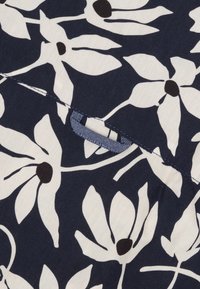 Marine stof met een bloemenpatroon van witte bloemblaadjes en zwarte centra. Inclusief een blauw gestikte tab voor gemakkelijk vastpakken.