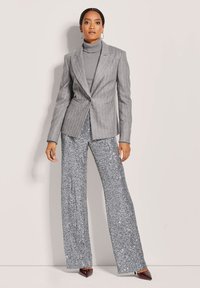 Gray pinstriped blazer over a matching turtleneck, paired with silver sequin wide-leg trousers, and pointed toe heels.
