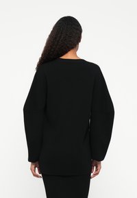 Μαύρος oversized πουλόβερ με μακριά, ογκώδη μανίκια, ριμπ ύφανση και στρογγυλή λαιμόκοψη, προσφορά χαλαρής εφαρμογής.