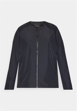 Marineblauwe lichtgewicht jas met ronde halslijn, volledige rits aan de voorkant en lange mouwen. Glad, waterafstotend materiaal met minimale details.