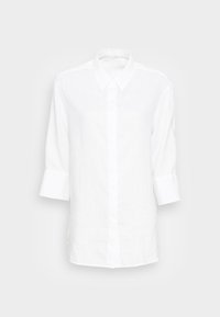 Chemise en lin blanc avec un col classique, des manches longues à poignets et un devant à boutons. Texture lisse et design léger.
