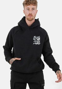 Sudadera negra con bolsillo frontal, capucha con cordón y diseño gráfico blanco en el lado izquierdo del pecho. Fabricada con tejido suave y puños de canalé.