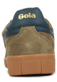 Bruine suède sneakers met blauwe leren accenten, voorzien van een gevoerde zool en een gouden "Gola" logo op de hiel. Gevoelige textuurdetails zichtbaar.