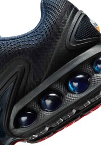 Scarpa sportiva blu scuro con upper in rete testurizzata, suola in gomma nera e capsule di ammortizzazione d'aria visibili in blu e nero.