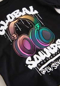 Schwarzer Pullover mit buntem Motiv, das große Kopfhörer, den Schriftzug "GLOBAL SOUNDS" und einen tropfenden Farbeffekt zeigt, der lebendige Farben hervorhebt.