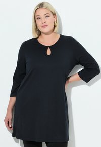 Musta tunika, jossa on pyöreä pääntie ja avainaukko-yksityiskohta. Kolmen neljänneksen hihat ja rento istuvuus. Suloinen tekstuuri ja kevyt materiaali.