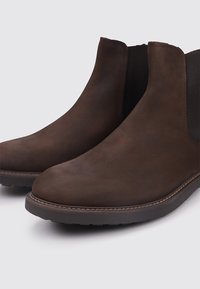 Bottines en cuir marron avec une texture lisse, bout rond, panneaux latéraux élastiques et semelle en caoutchouc plate. Design minimaliste avec des accents de couture.