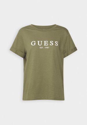 Olive green short-sleeve t-shirt made of soft fabric, featuring white printed text "GUESS EST. 1981" across the chest. Rolled cuffs present.