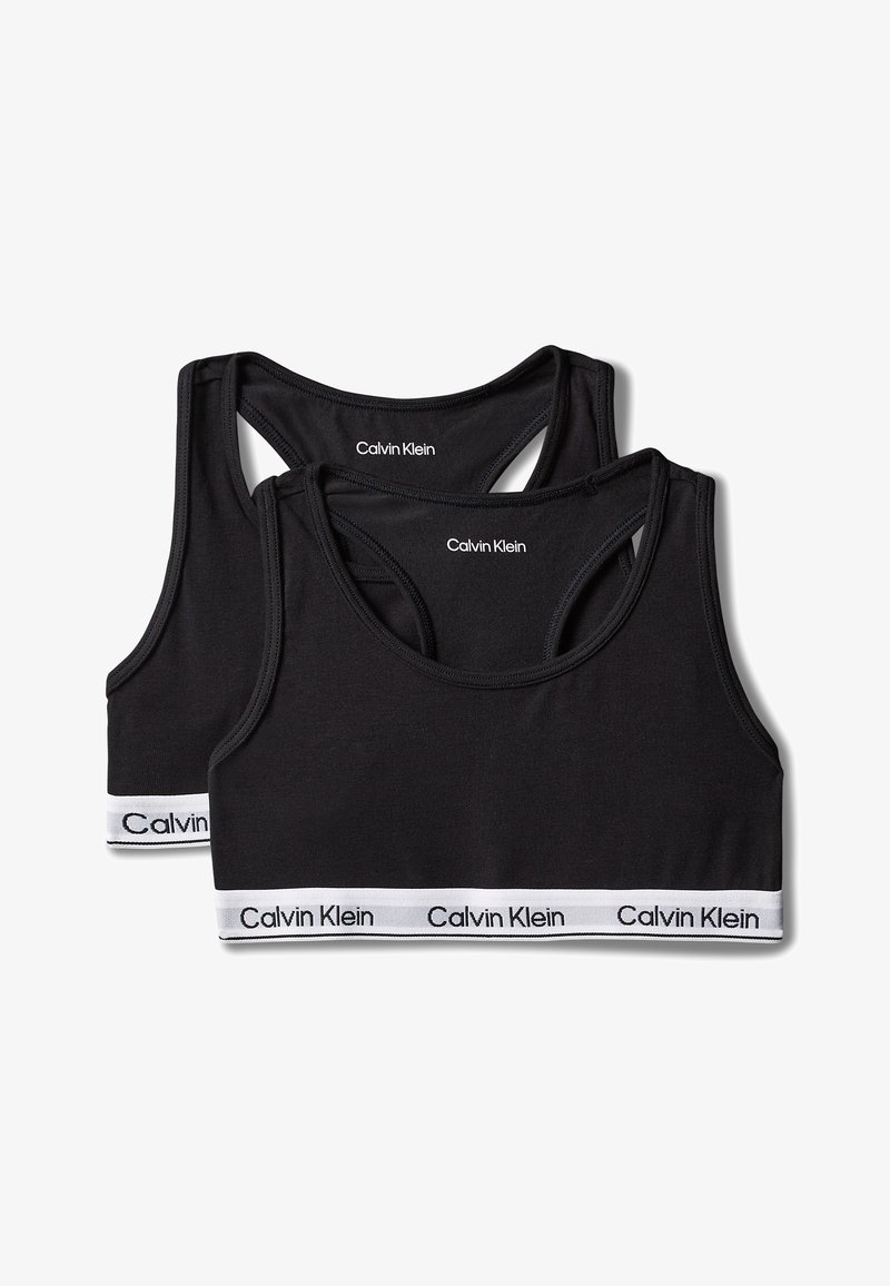 Kaks musta Calvin Klein spordirinnahoidjat racerback disainiga ja valgete elastsete bändidega, millel on Calvin Kleini logo musta tekstiga.