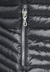 Black puffer jacket fabric with quilted texture, featuring a metallic zipper and pull tab along the center. Smooth sheen finish.