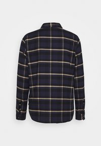 Camicia a quadri blu navy con controlli beige e neri, maniche lunghe e polsini abbottonati. Il tessuto sembra morbido con un design a colletto classico.