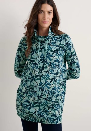 Langdruk tuniek in groen en blauw bloempatroon, met een colkraag, voorzakken en een relaxte pasvorm. Gemaakt van zachte stof.