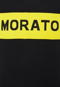 Černá pletenina s výrazným horizontálním žlutým pruhem nesoucím text "MORATO" tučnými černými písmeny.
