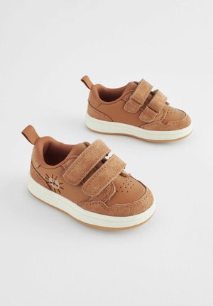 Brune sneakers med to velcrobånd, en tekstureret ruskindsoverflade, perforeret forfod og en hvid gummisål. Har en logoaccent.