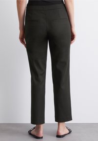 Pantalons ajustés vert foncé avec une texture lisse. Dotés d'une taille mi-haute, de deux poches arrière et de jambes droites raccourcies.