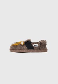 Zapatilla de felpa marrón con diseño de león, banda elástica negra y suela texturizada. Presenta acentos bordados y una etiqueta de logo en el lateral.