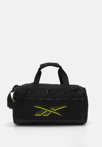Black duffel bag made of durable fabric, featuring a zippered top, dual handles, and a bold yellow Reebok logo on the front.