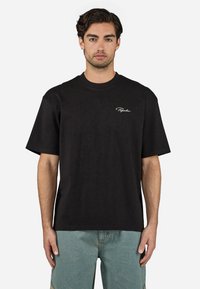 Black cotton t-shirt with a round neck and short sleeves. Features white embroidered logo on the left chest. Casual fit, smooth texture.