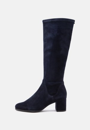 Hoher dunkelblauer Wildlederstiefel mit abgerundeter Spitze und mittelhohem Blockabsatz, von der Seite auf weißem Hintergrund gezeigt.