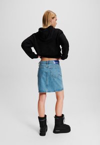 Črn skrajšan hoodie, modra denim krilo z zadaj žepi in črne gležnjarje z debelim podplatom ter umetnim krznom.