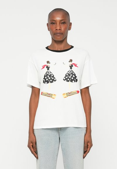 Weißes T-Shirt mit schwarzem Ausschnitt, das ein grafisches Design von zwei stilisierten Figuren in gepunkteten Kleidern, roten Akzenten und gelben Plateauschuhen zeigt.